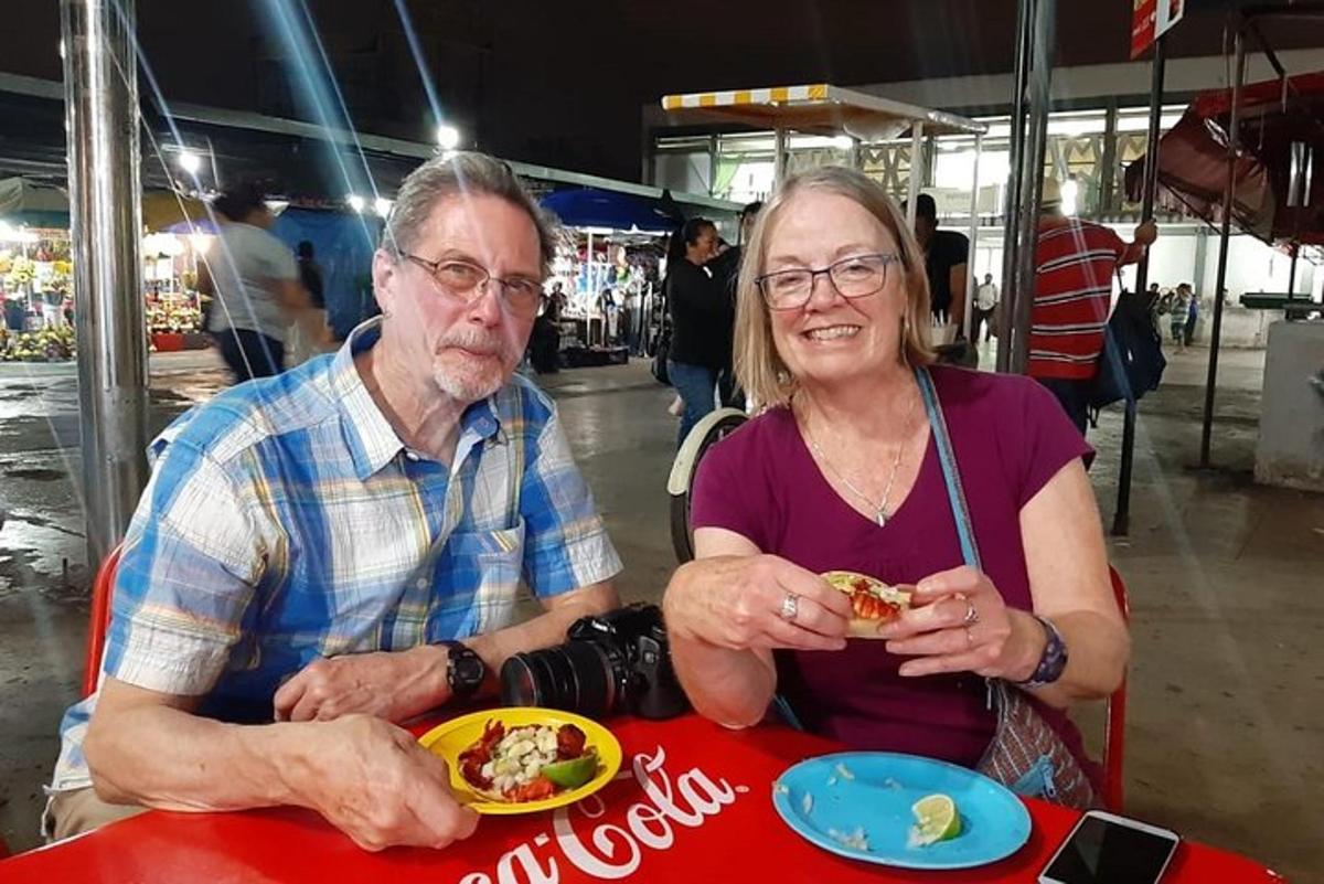 um homem e uma mulher sentados à mesa comendo comida