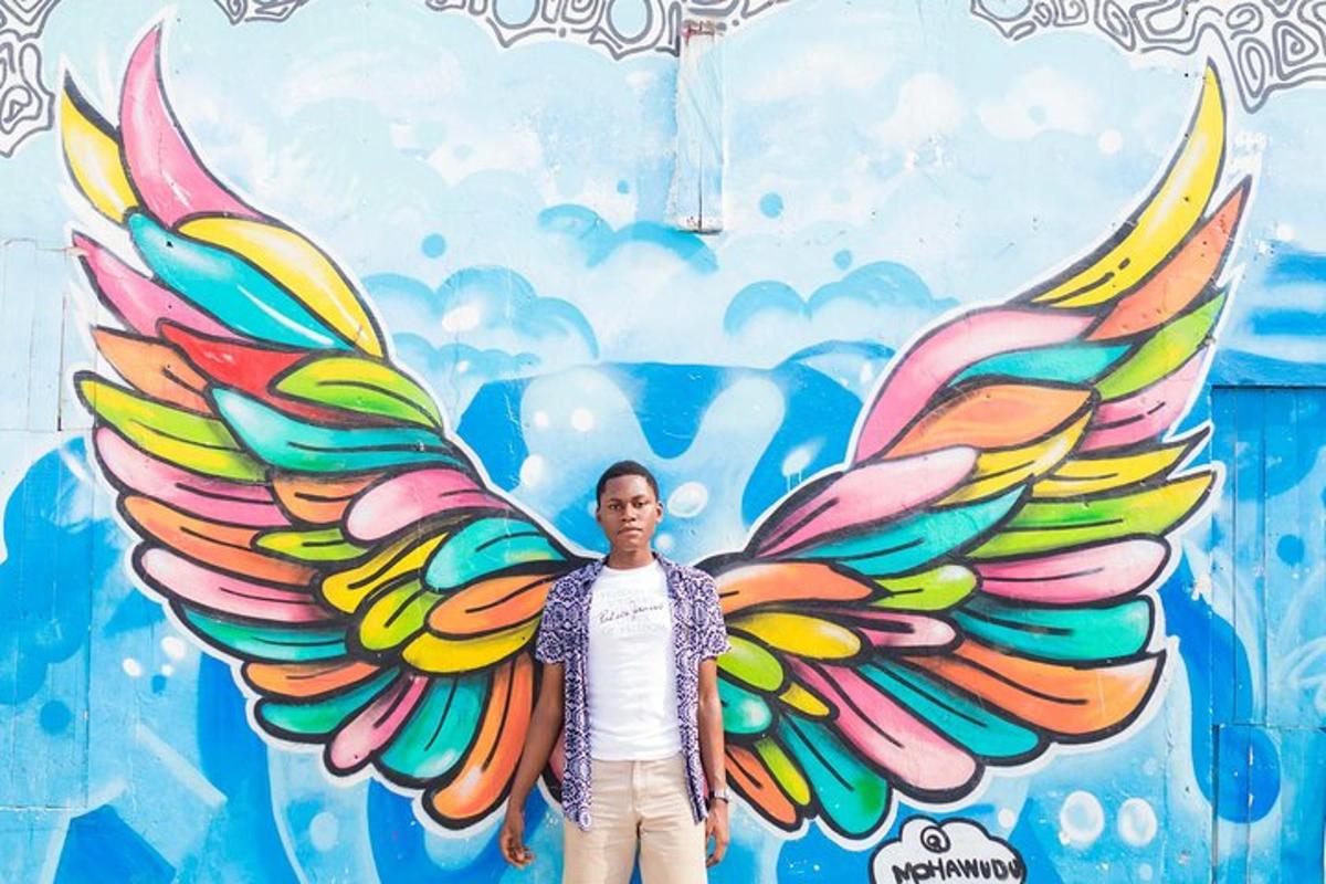 a man standing in front of a mural with wings