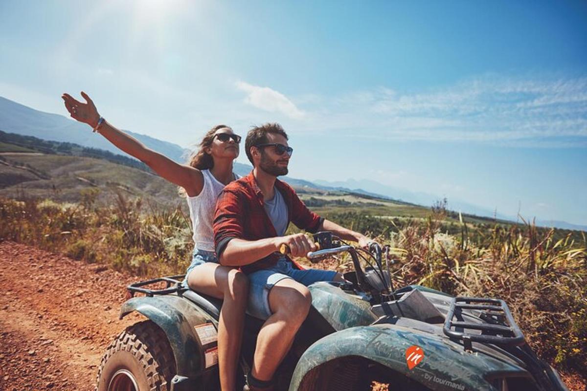 Un hombre y una mujer viajando en un quad por un camino de tierra