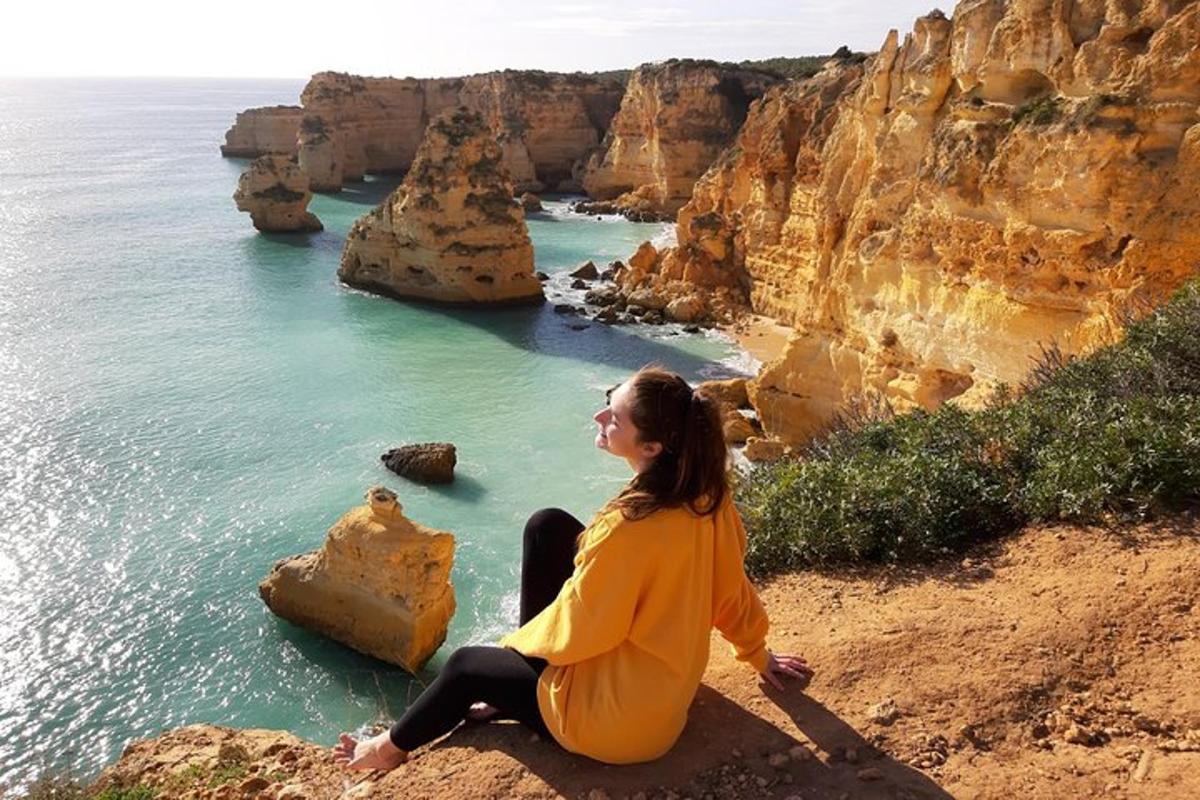 uma mulher sentada em um penhasco com vista para o oceano