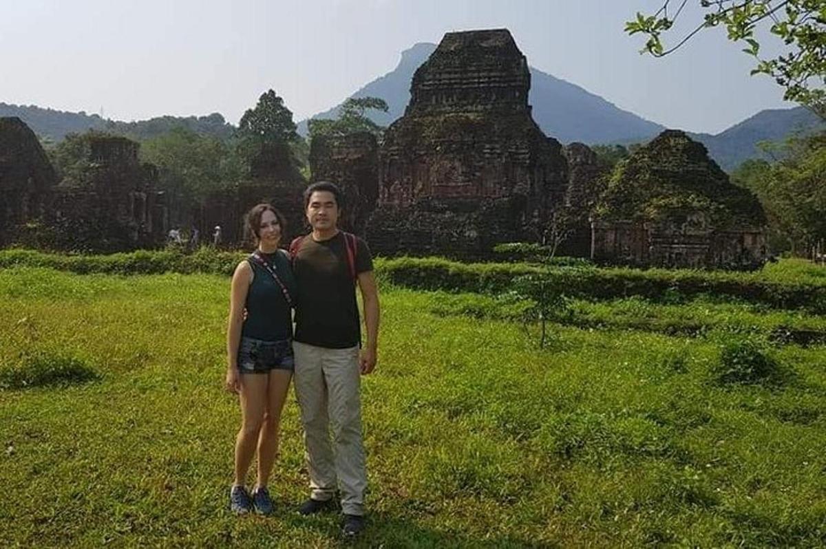 a man and woman standing in a field in front of a temple