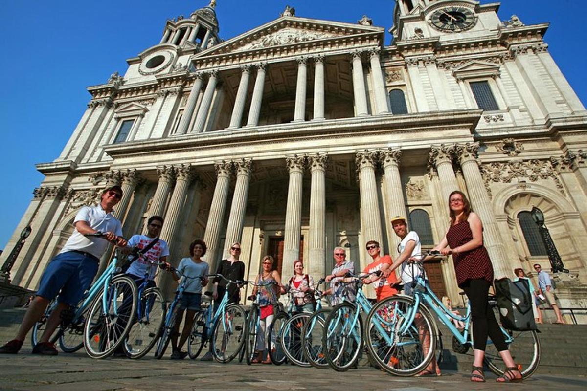 um grupo de pessoas em pé em frente a um prédio com bicicletas