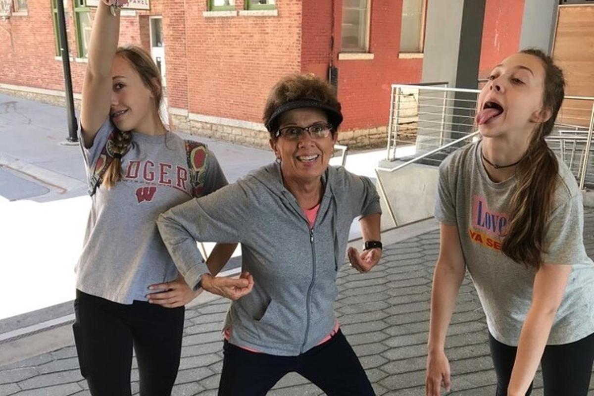 duas meninas e uma mulher mais velha dançando na rua