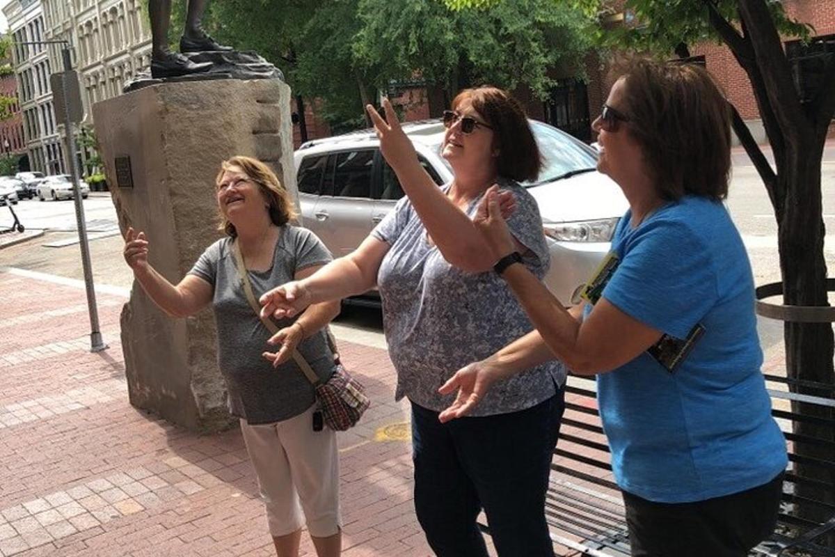 um grupo de três mulheres em pé ao lado de uma estátua
