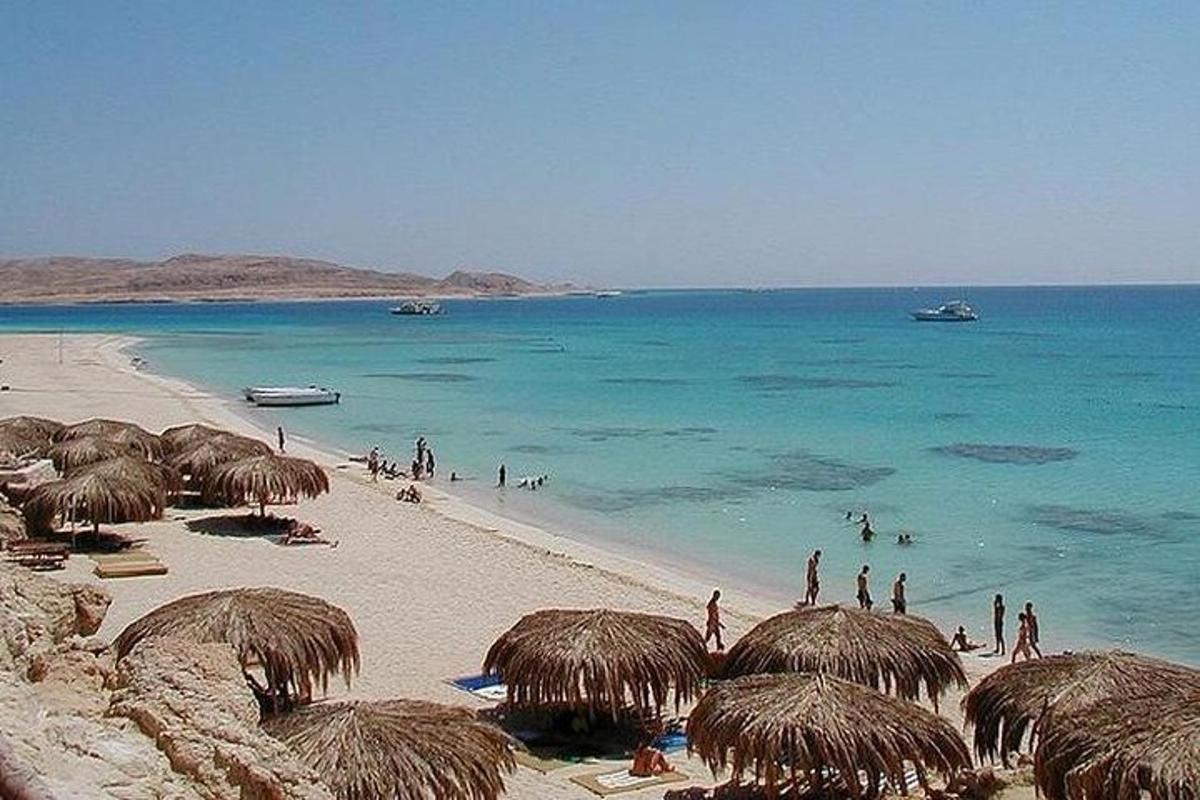 plaža sa slamnatim suncobranima i ljudima u vodi