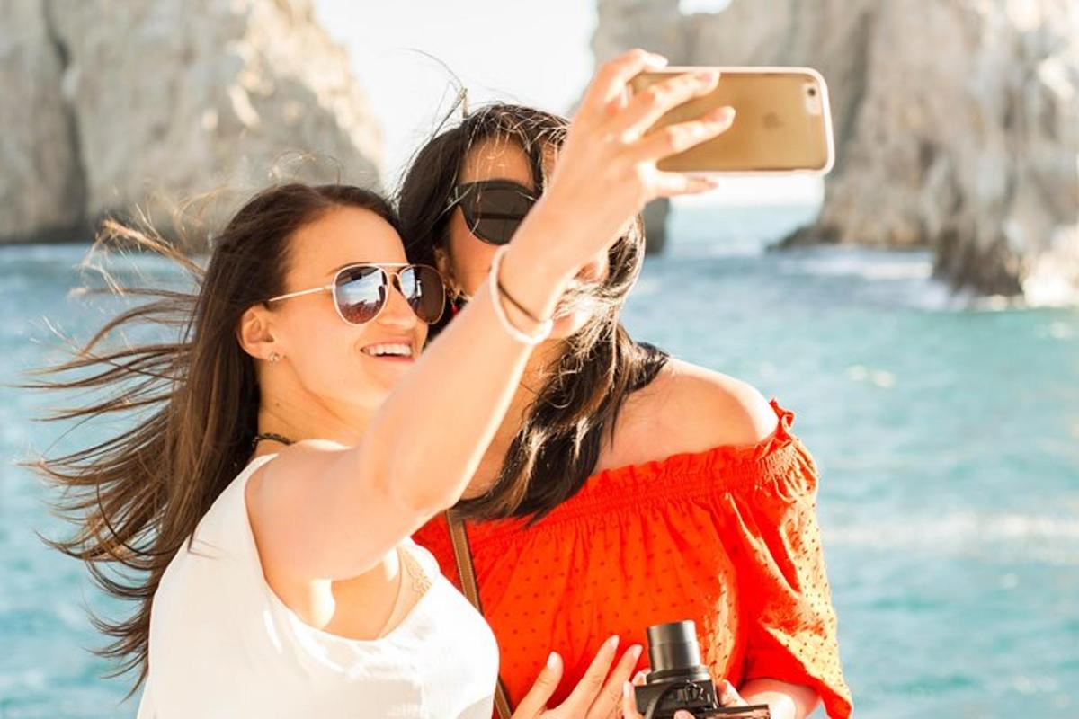 dua wanita mengambil gambar lautan dengan telefon bimbit