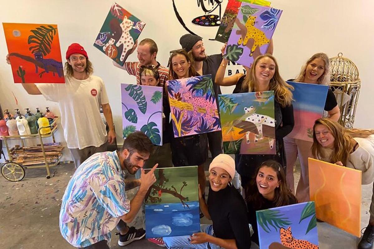 a group of people posing for a picture holding up paintings