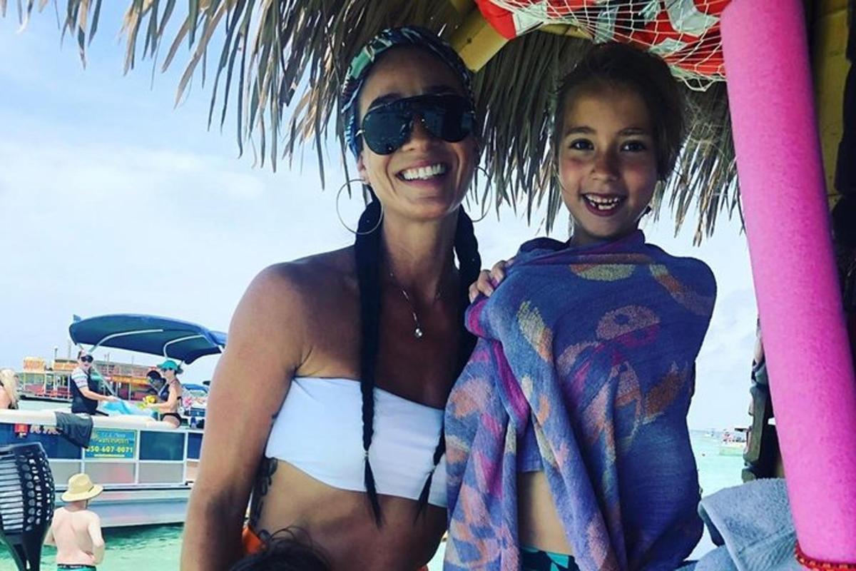 a woman and a child sitting under an umbrella on the beach