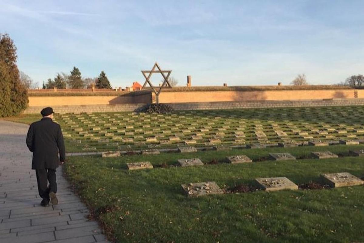 un uomo che cammina davanti a un cimitero