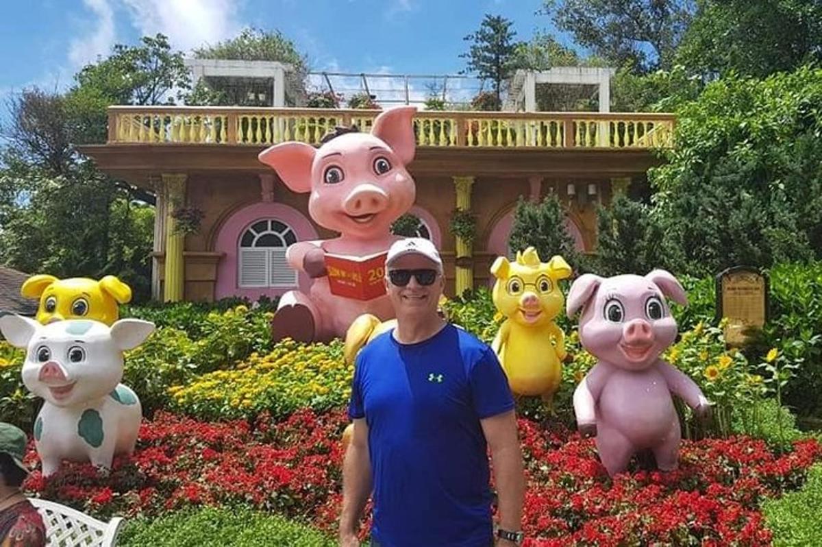a man standing in front of a garden with pig statues