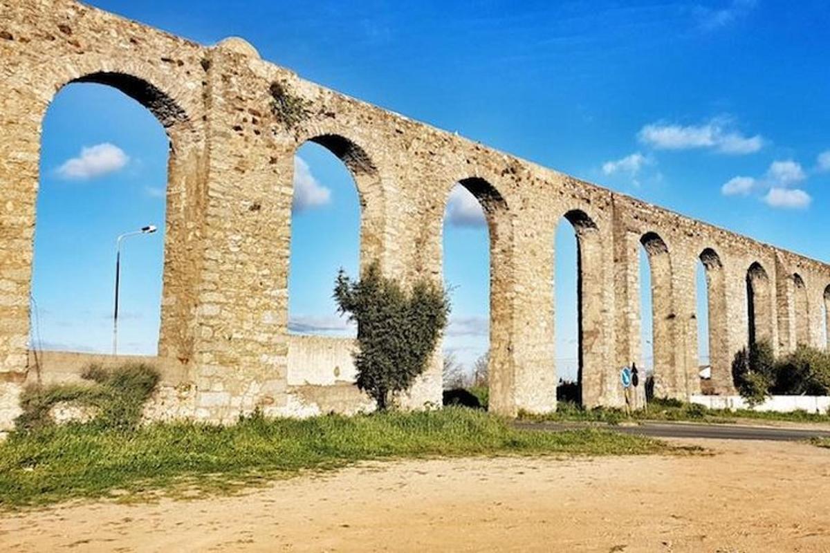 un vecchio ponte di pietra con archi sul lato di una strada
