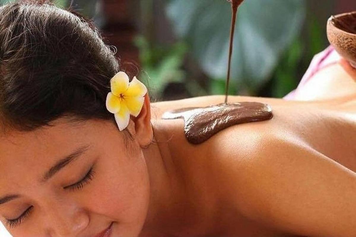 Una mujer recibiendo un masaje con una flor en la espalda.