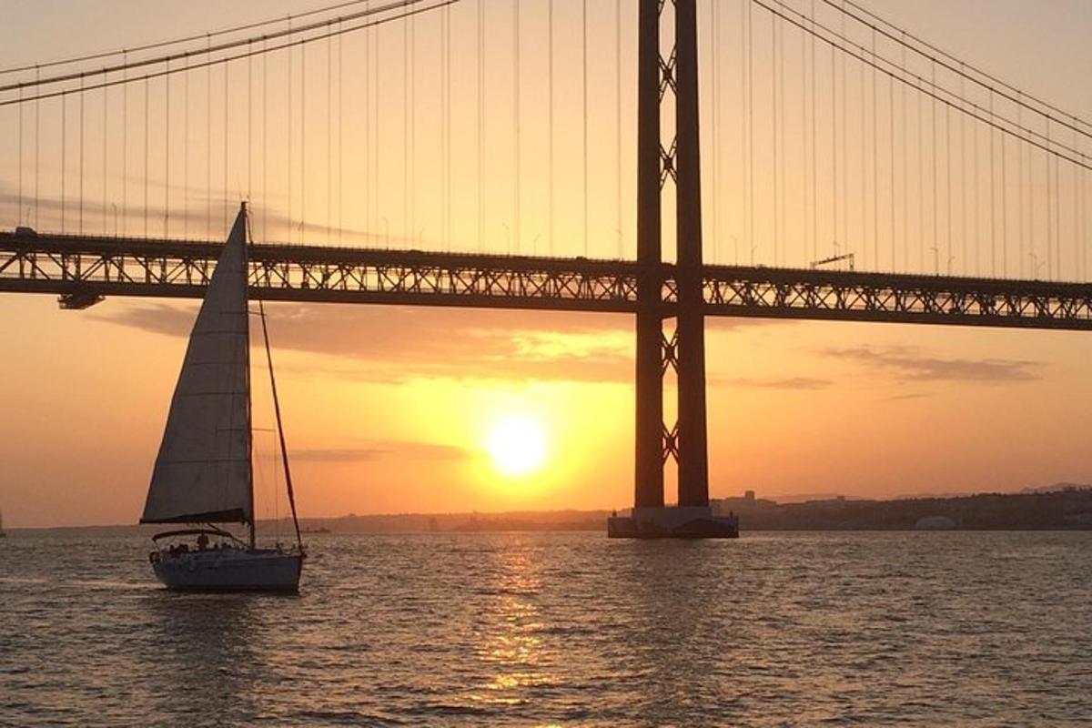 a sailboat in front of a bridge at sunset