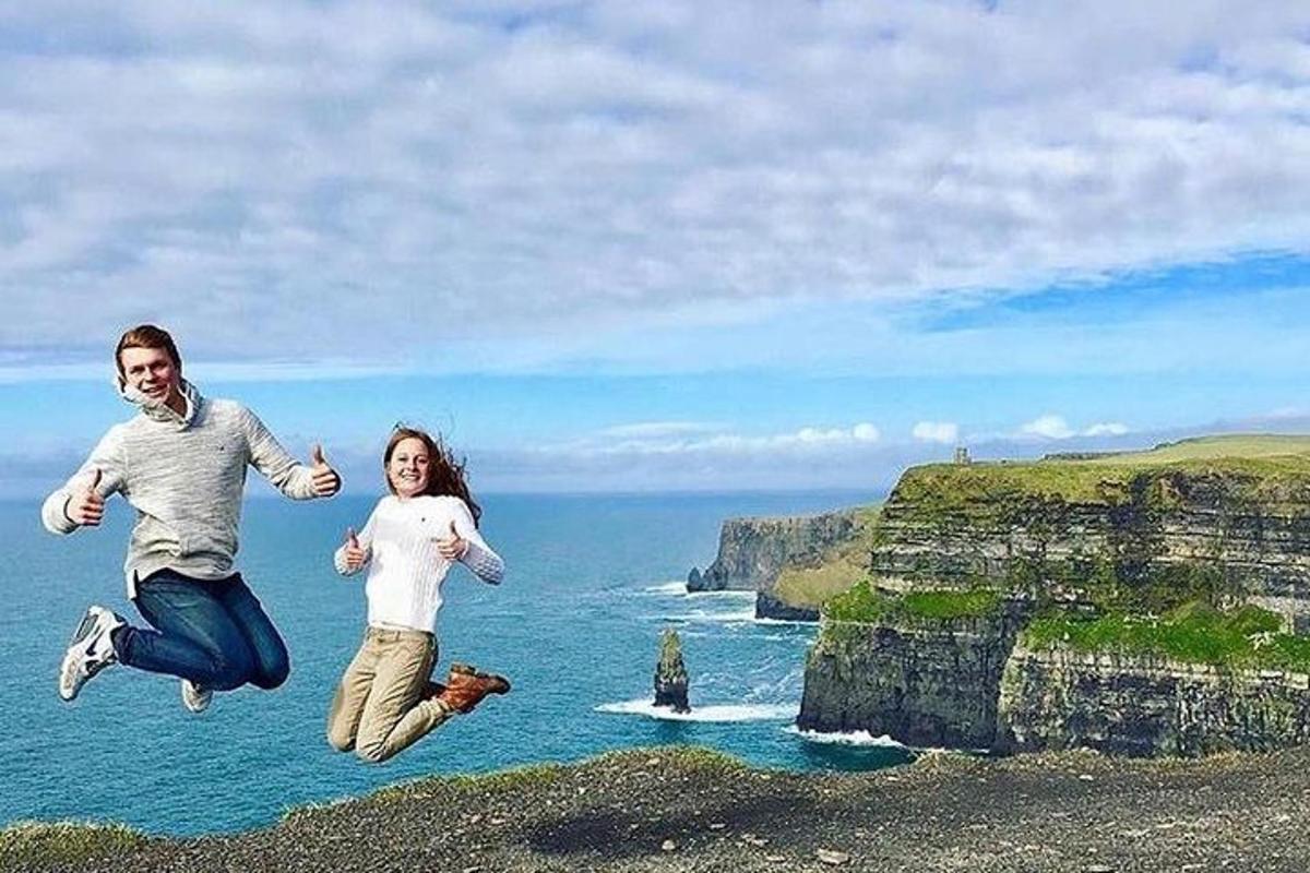 Un hombre y una mujer saltando en el aire cerca del océano.