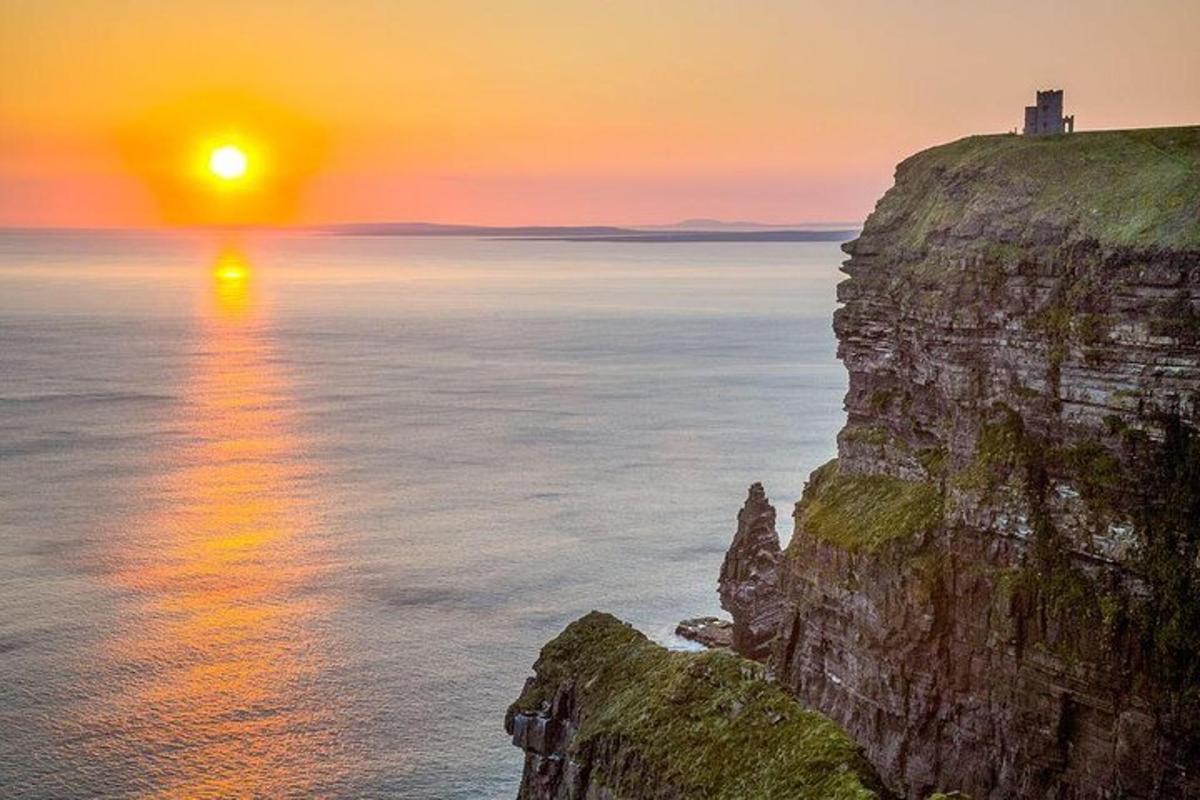 Západ slunce nad oceánem s majákem na útesu