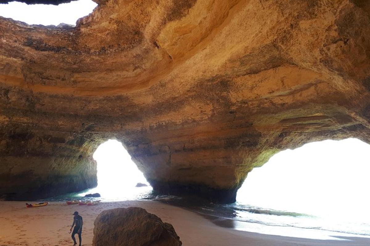 a man standing in front of a cave on the beach