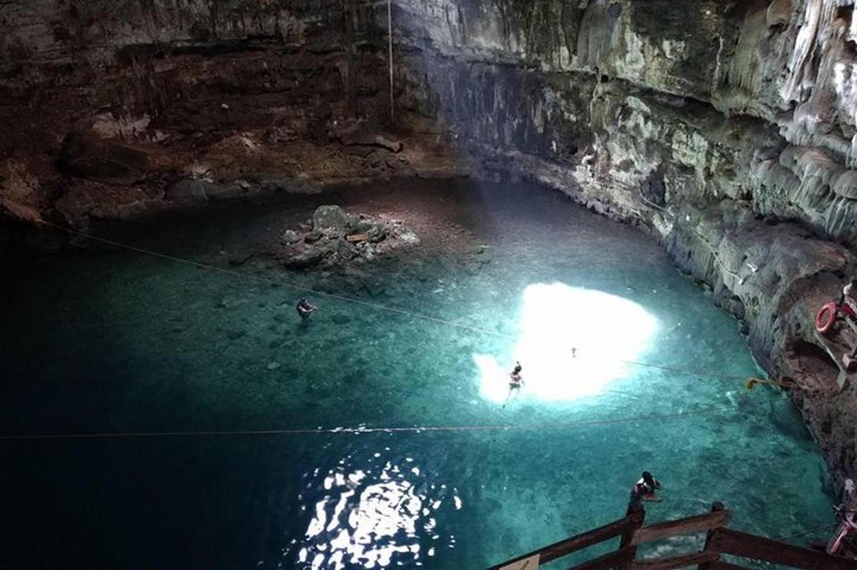 una grotta con persone che nuotano in una pozza d'acqua