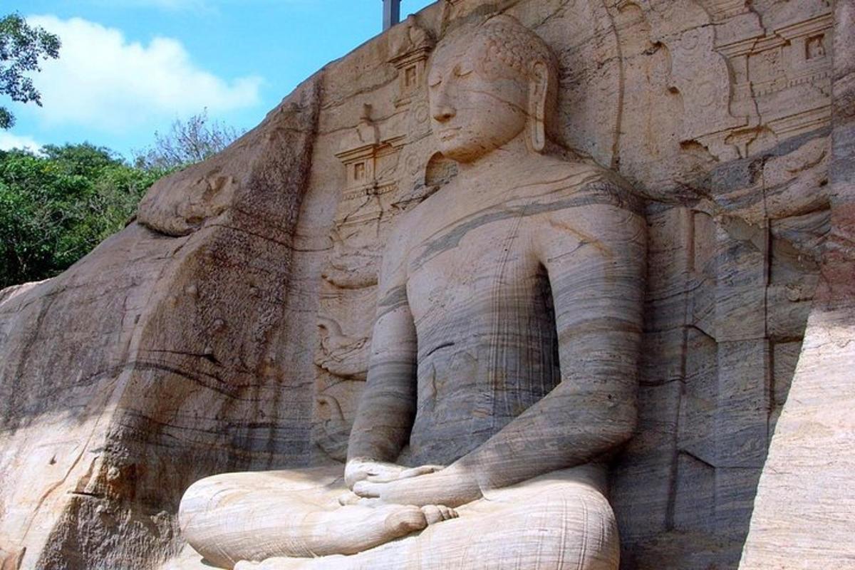 uma estátua de uma mulher sentada em uma parede de rocha