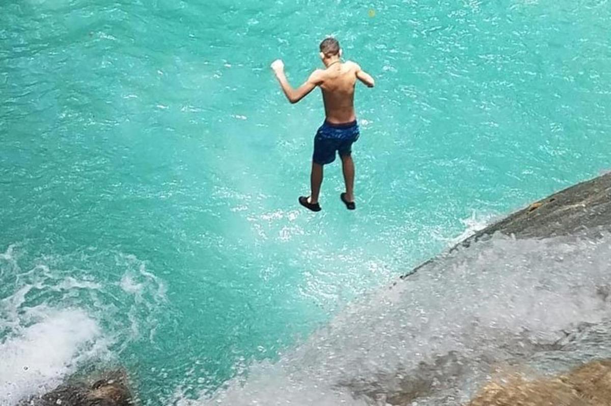 um homem pulando na água com um frisbee