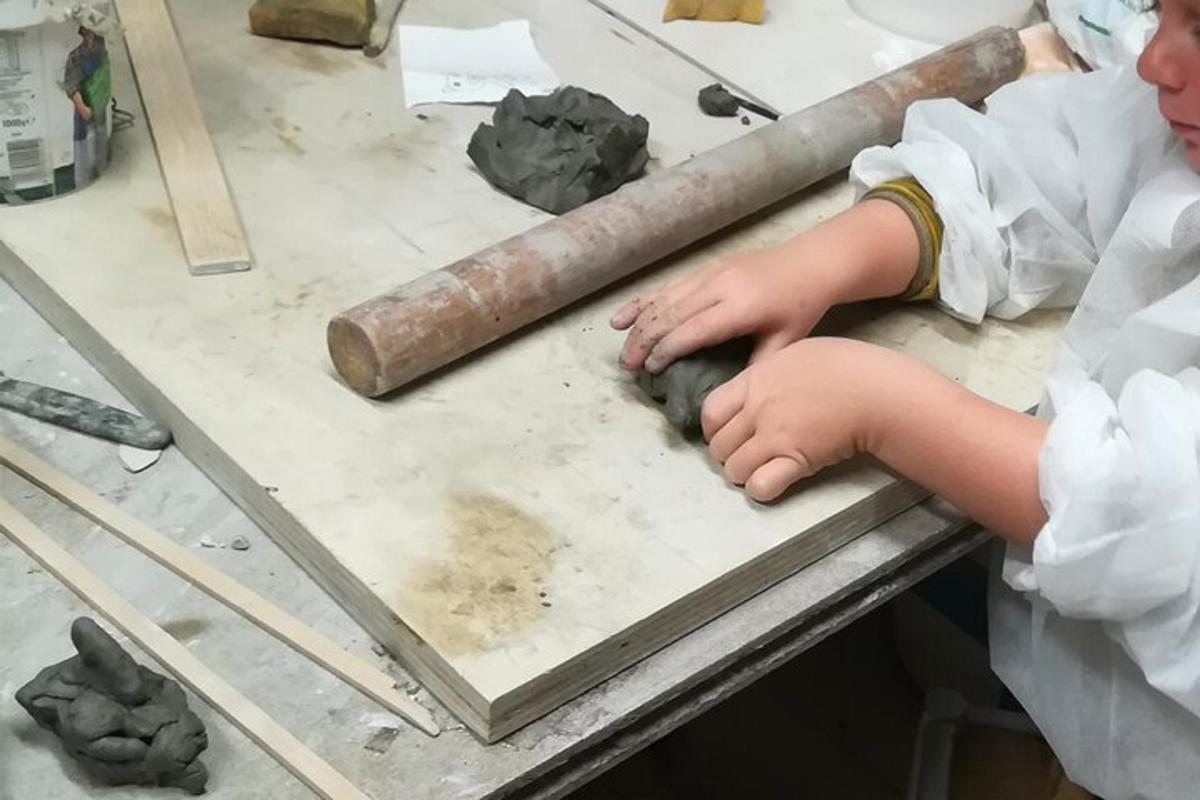 un băiat tânăr care lucrează la un proiect din lut pe o masă