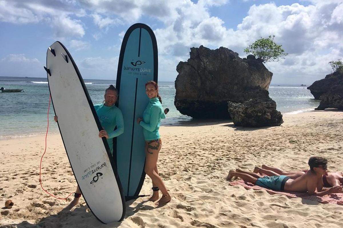 a man and woman standing next to surfboards on the beach