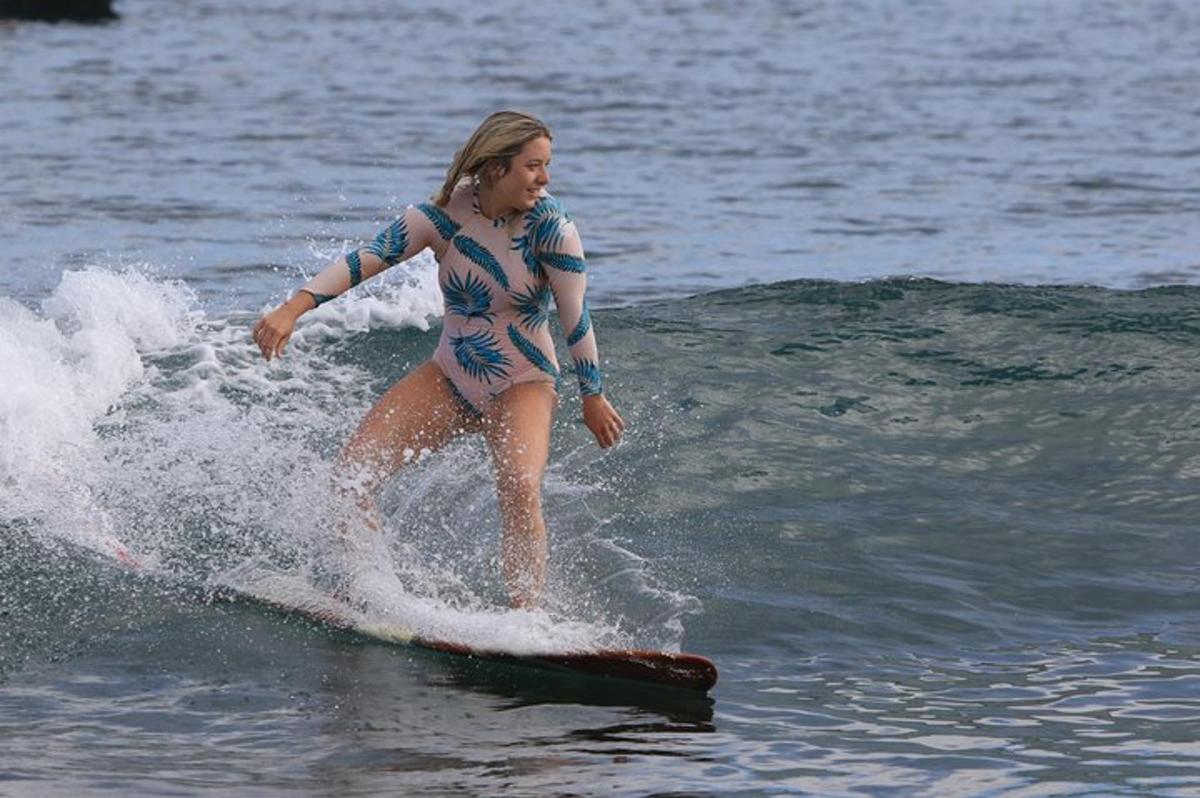 uma mulher surfando uma onda em uma prancha de surfe na água