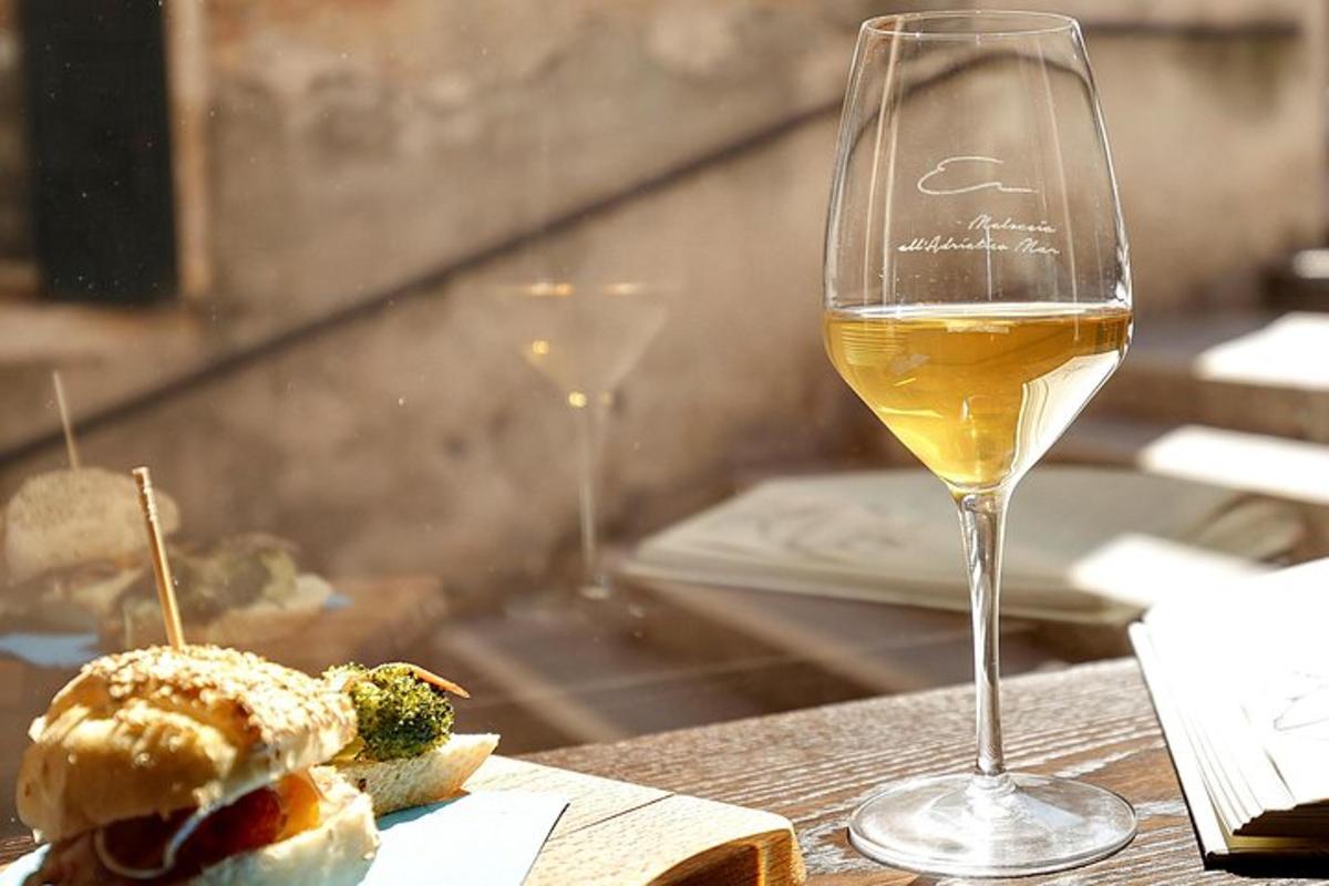 ein Glas Weißwein und ein Sandwich auf einem Tisch