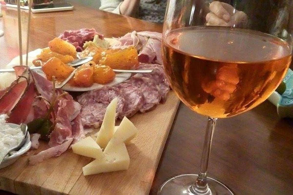 uma taça de vinho ao lado de um prato de carne e queijo