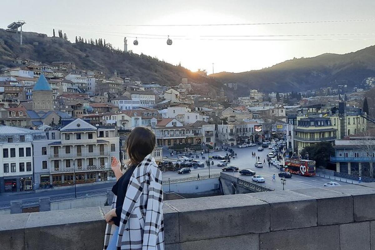 Una mujer parada en una cornisa mirando una ciudad