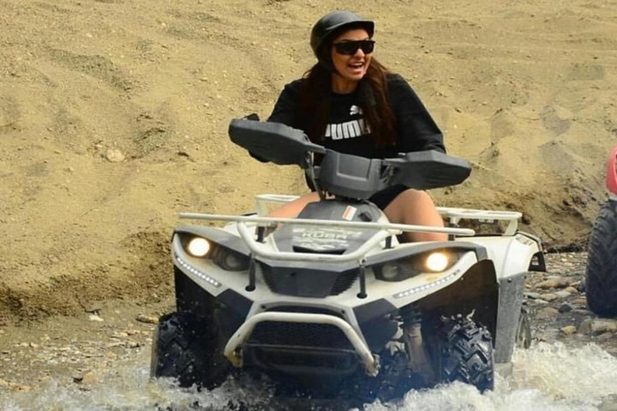 a woman riding a quad bike through the water