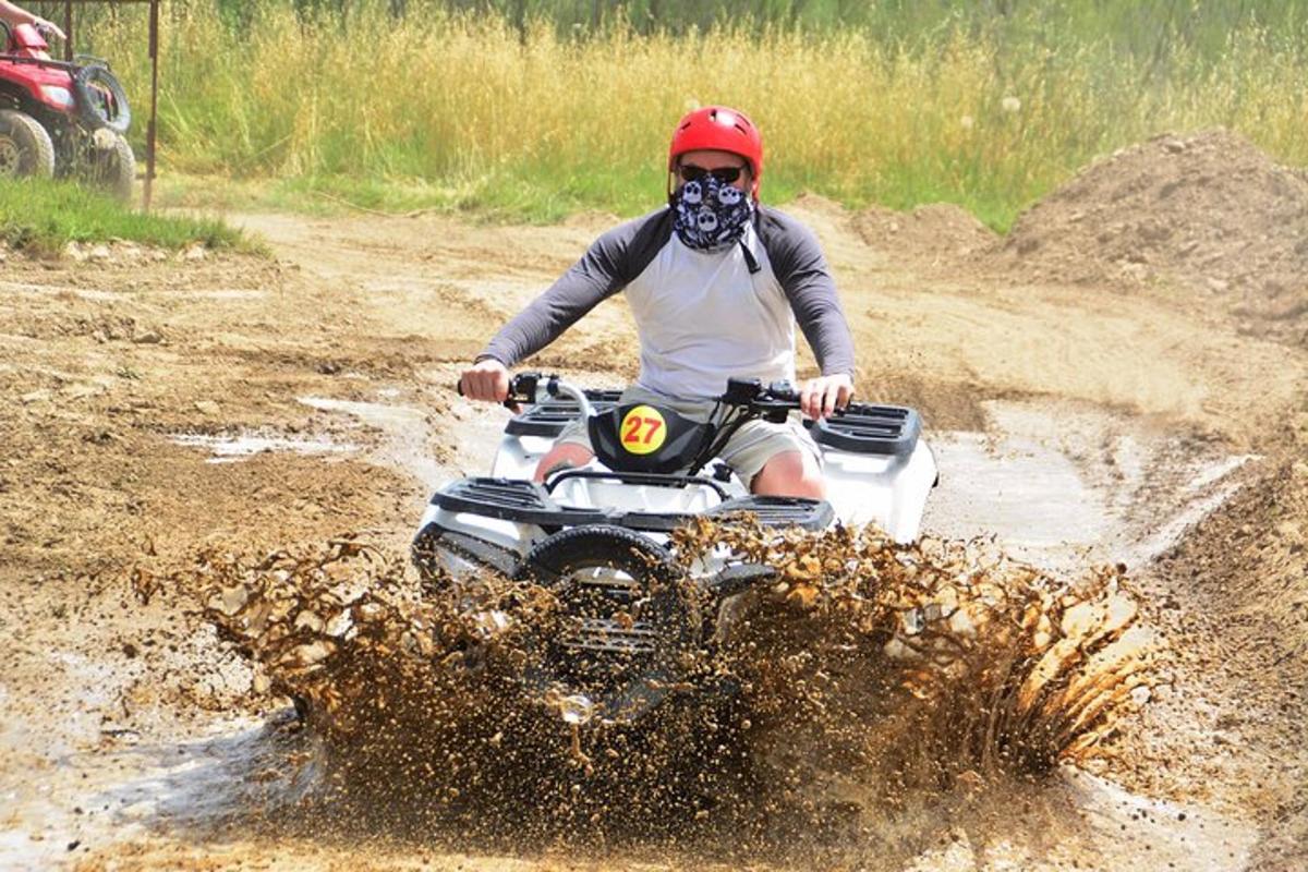 a man riding a fourwheeler through a mud loggedescription