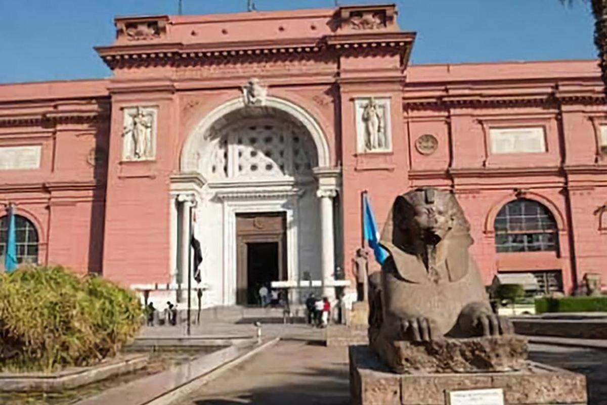 Un gran edificio rosa con una estatua delante.