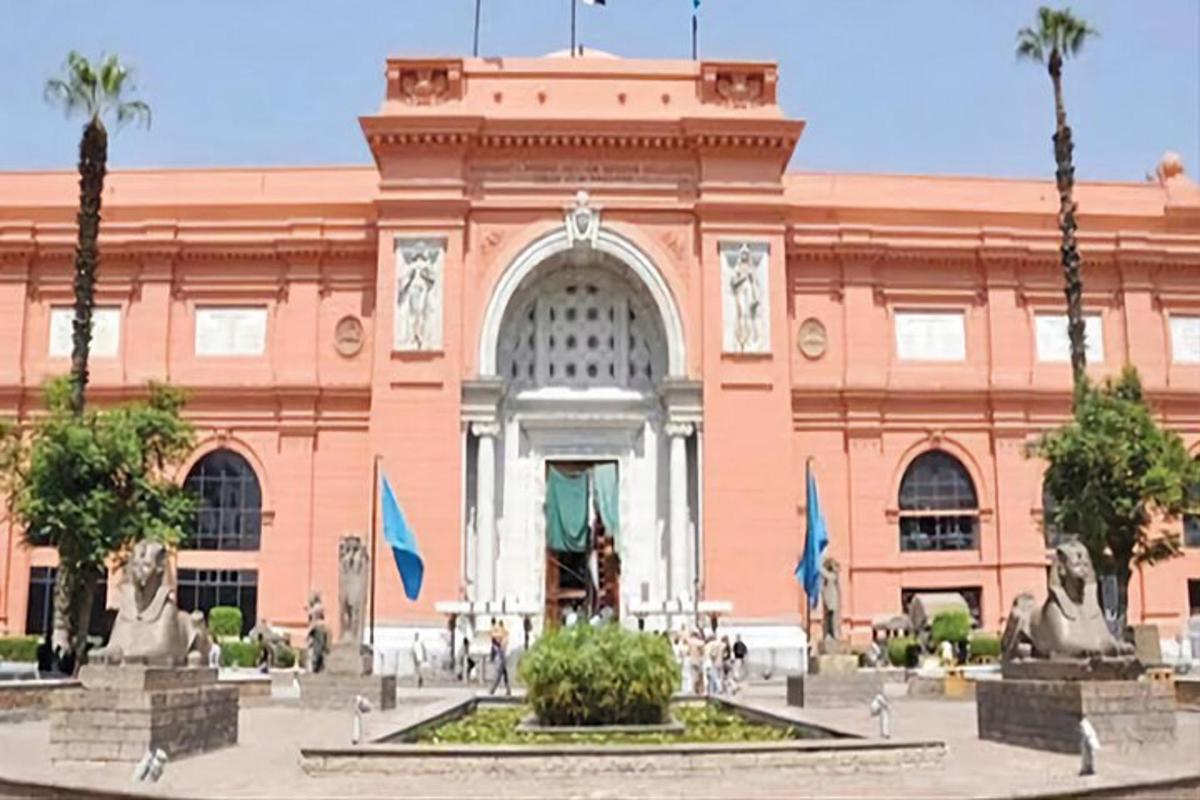 Un gran edificio rosa con una fuente delante.