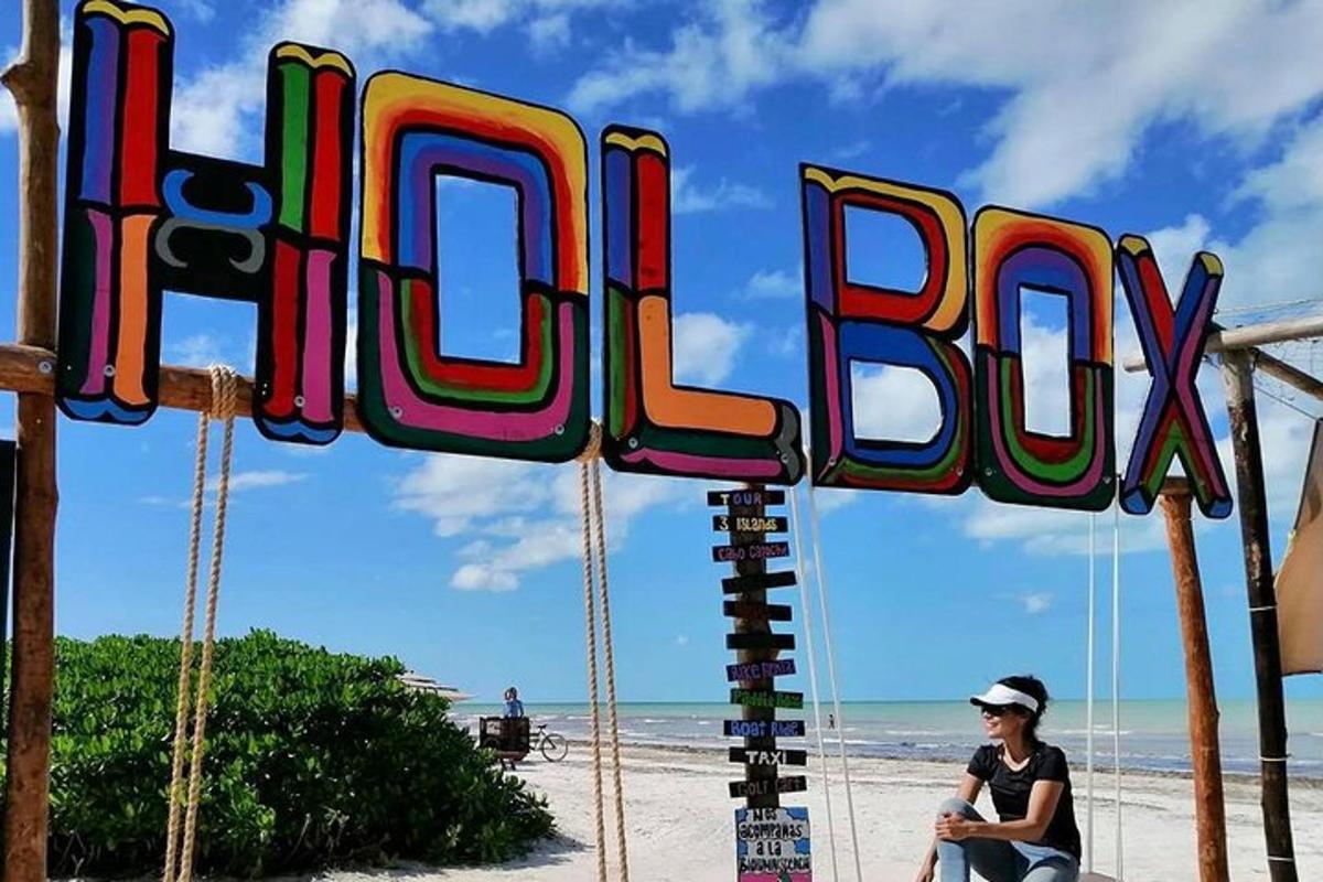 a person sitting under a sign on the beach
