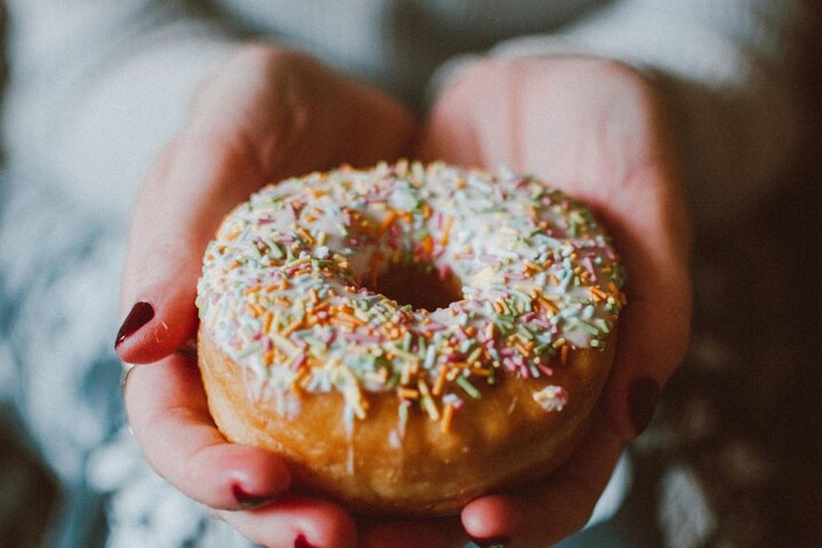 a person holding a donut with sprinkles