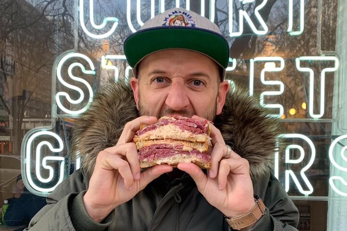 a man eating a large sandwich in front of a store