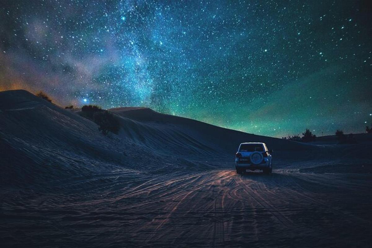 un'auto che percorre una strada sterrata sotto un cielo stellato