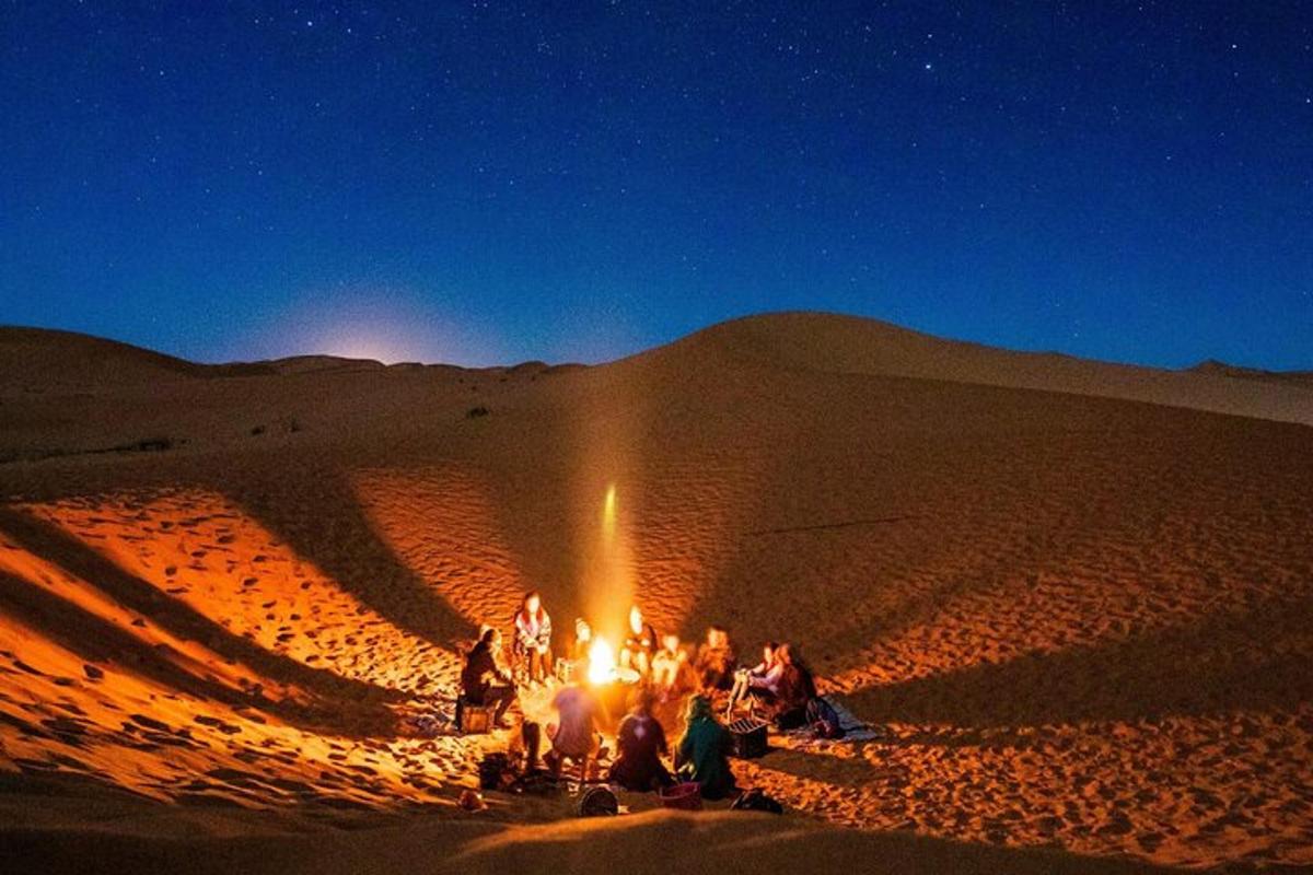 eine Gruppe von Menschen sitzt um ein Feuer in der Wüste