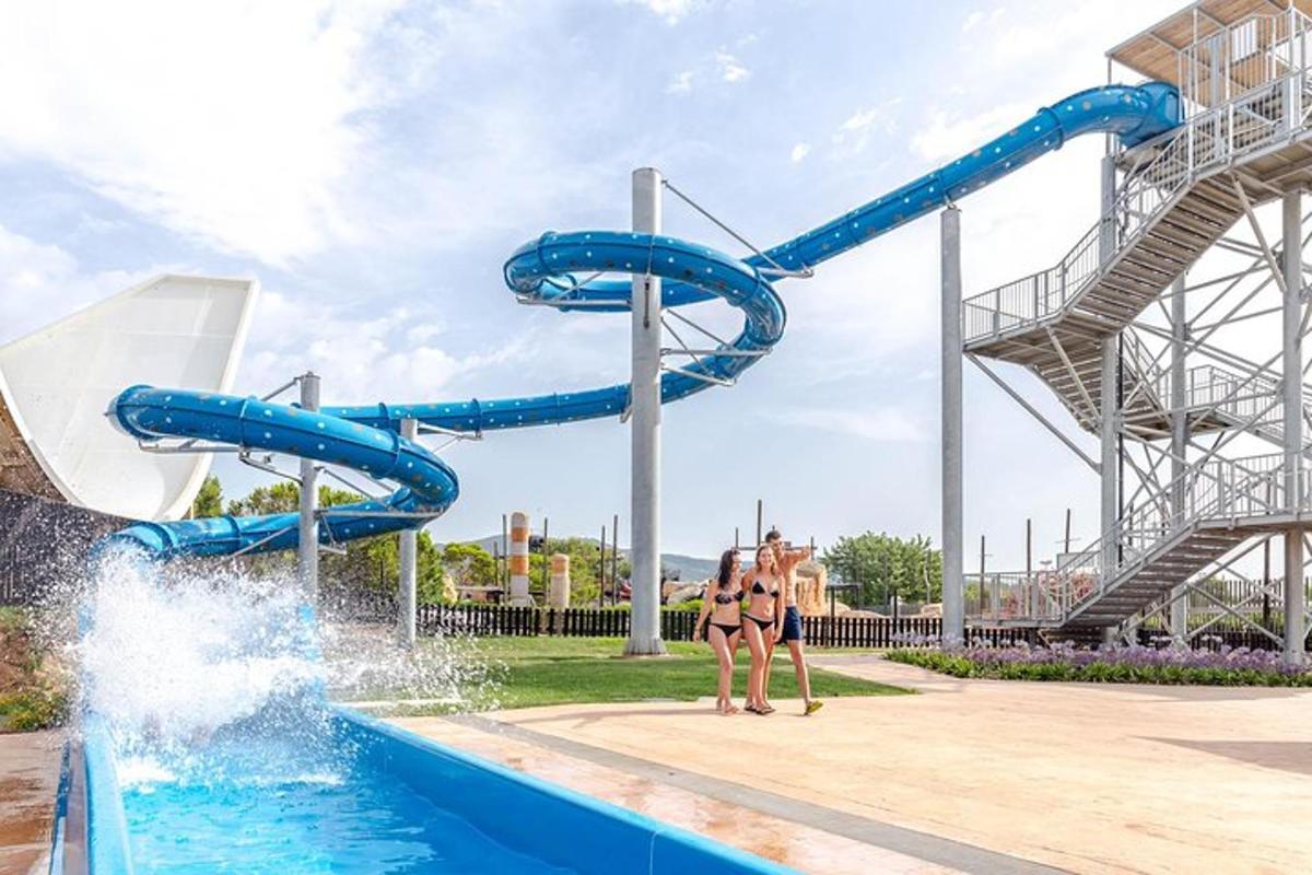 Dos personas paradas frente a un tobogán de agua en un parque acuático.