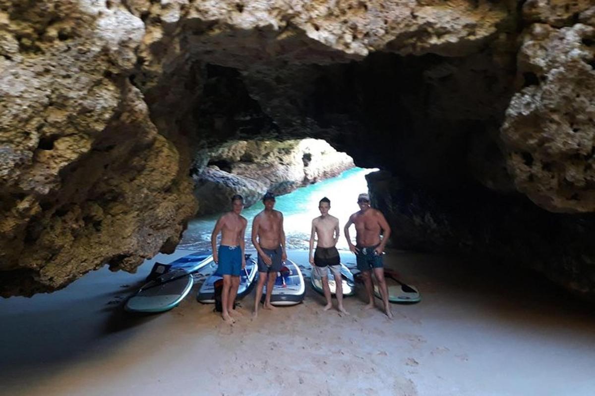un grup de trei bărbați care stau într-o peșteră cu plăcile lor de surf