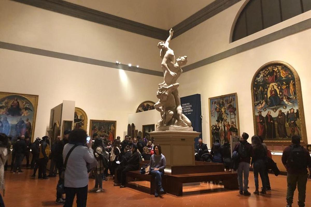 una folla di persone che guarda una statua in un museo