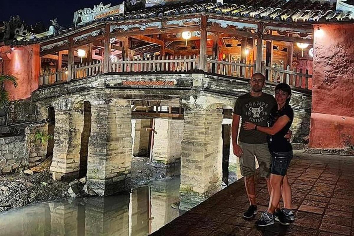 two men standing in front of a stone bridge