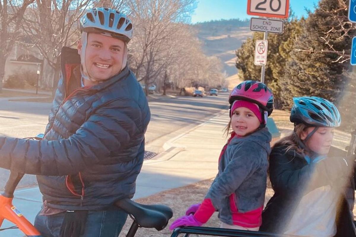 Un hombre y dos niños con cascos en una bicicleta