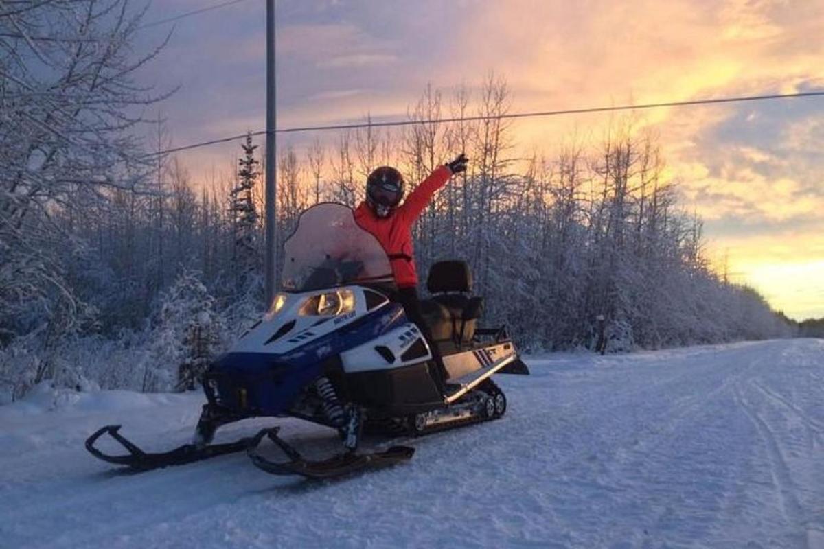 a man riding a snowmobile down a snow covered road