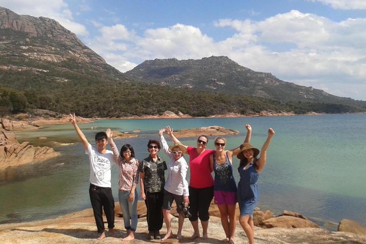 un grup de persones dretes sobre una roca a prop de l'aigua