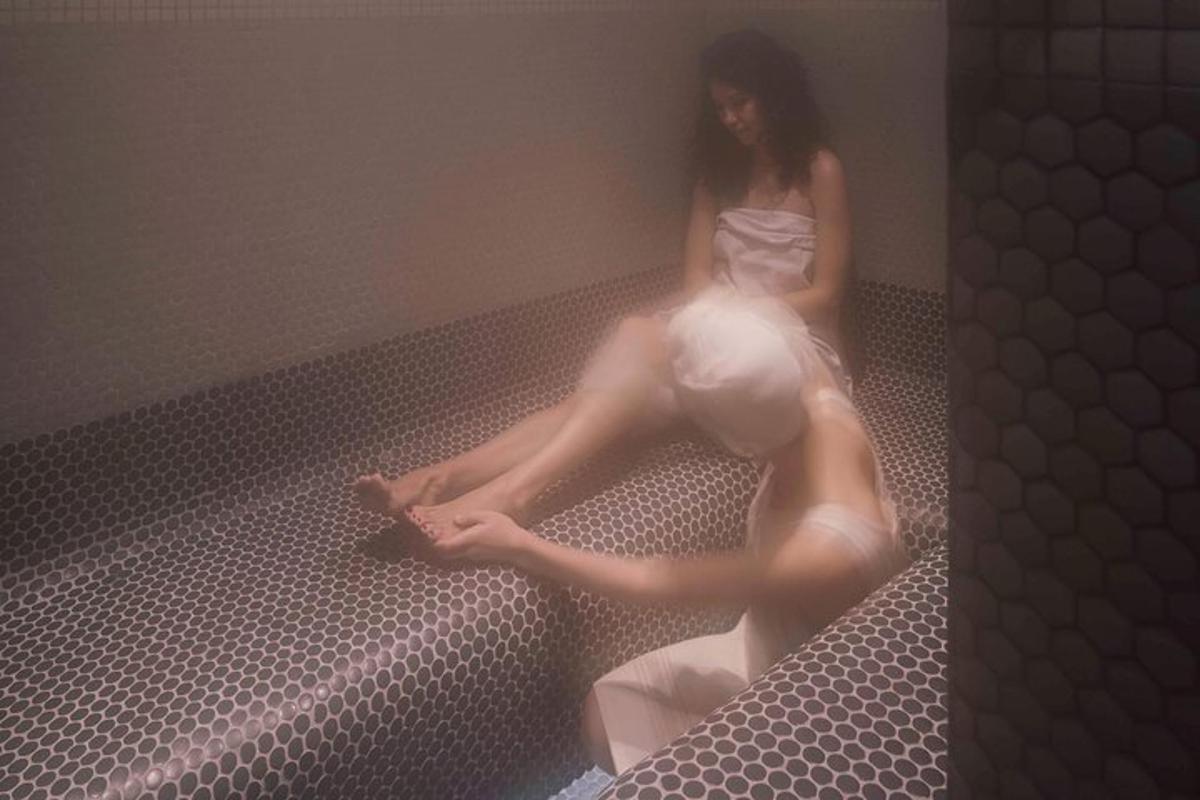 una donna in abito bianco seduta su un letto