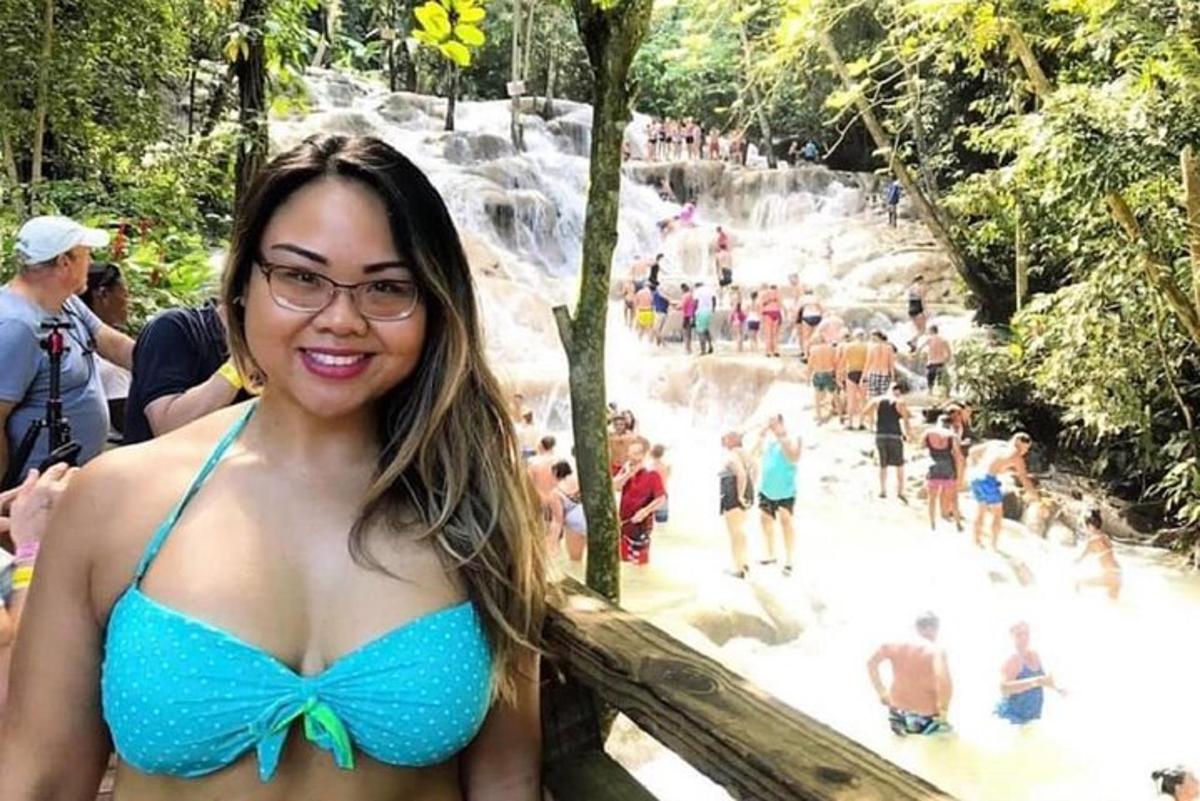 kobieta w niebieskim bikini stojąca przed wodospadem