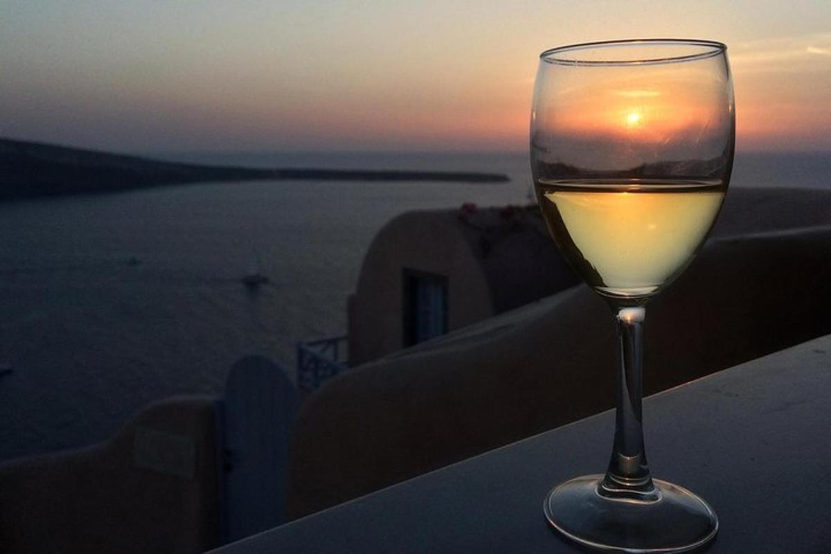 ein Glas Wein auf einem Felsvorsprung sitzend mit dem Sonnenuntergang