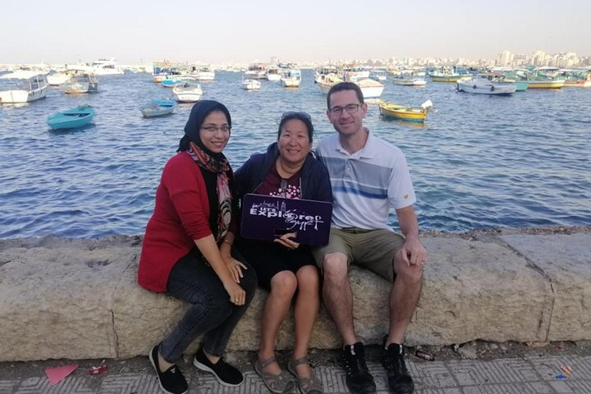 three people sitting on a wall near the water
