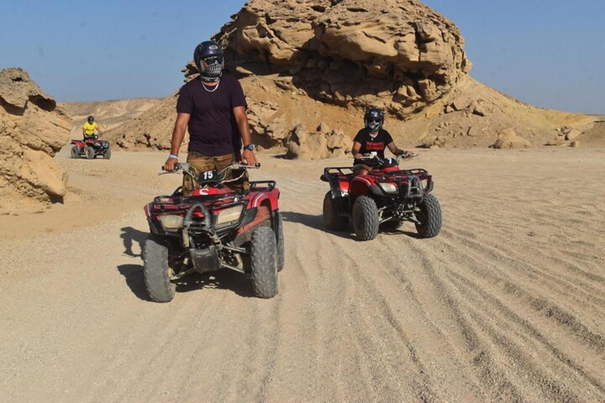seorang lelaki berdiri di sebelah dua atv di padang pasir